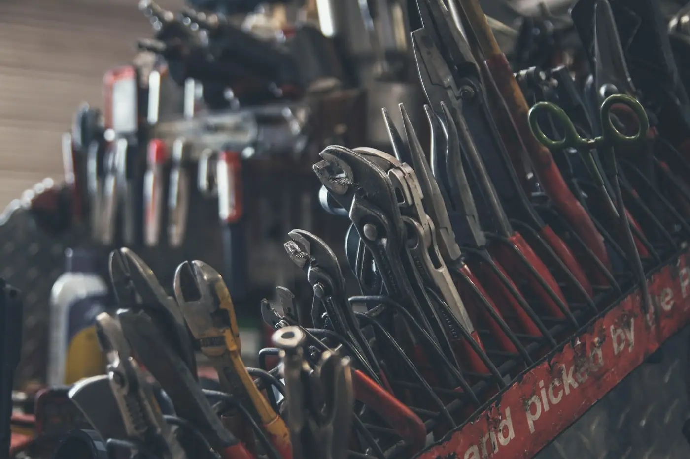 Close-up of pliers and hand tools racked in a workshop drawer